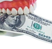 A denture mold holding a $100 bill.