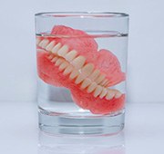 Dentures soak in glass of clear liquid