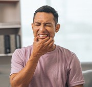 Man touching corners of mouth squinting in pain.