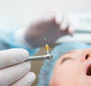 dentist holding dental implant during surgery 