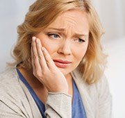 Woman holding cheek in pain before emergency dentistry