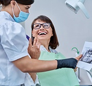Woman smiling with dentist while reviewing X-ray