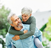 Senior couple smiling while hugging outside