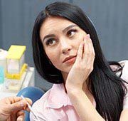 Woman holding cheek in pain before emergency dentistry