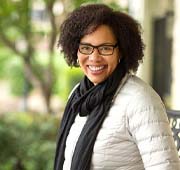 smiling woman wearing a white coat and black scarf