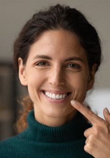 a woman pointing to her brightened teeth