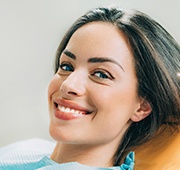 A smiling woman in the dentist chair after porcelain veneer treatment