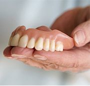 Hand holding a full denture