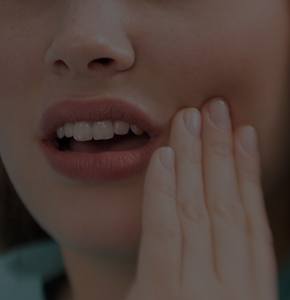 Closeup of patient holding cheek before emergency dentistry