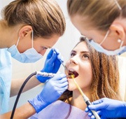 Salem dentist and dental assistant treating smiling patient's tooth