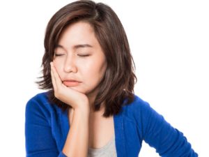 a woman holding her cheek in pain