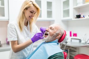 a man having his teeth checked by a dental hygienist