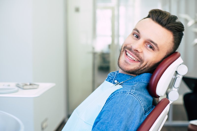 a young man with a beard smiling as he prepares to see his dentist in Salem